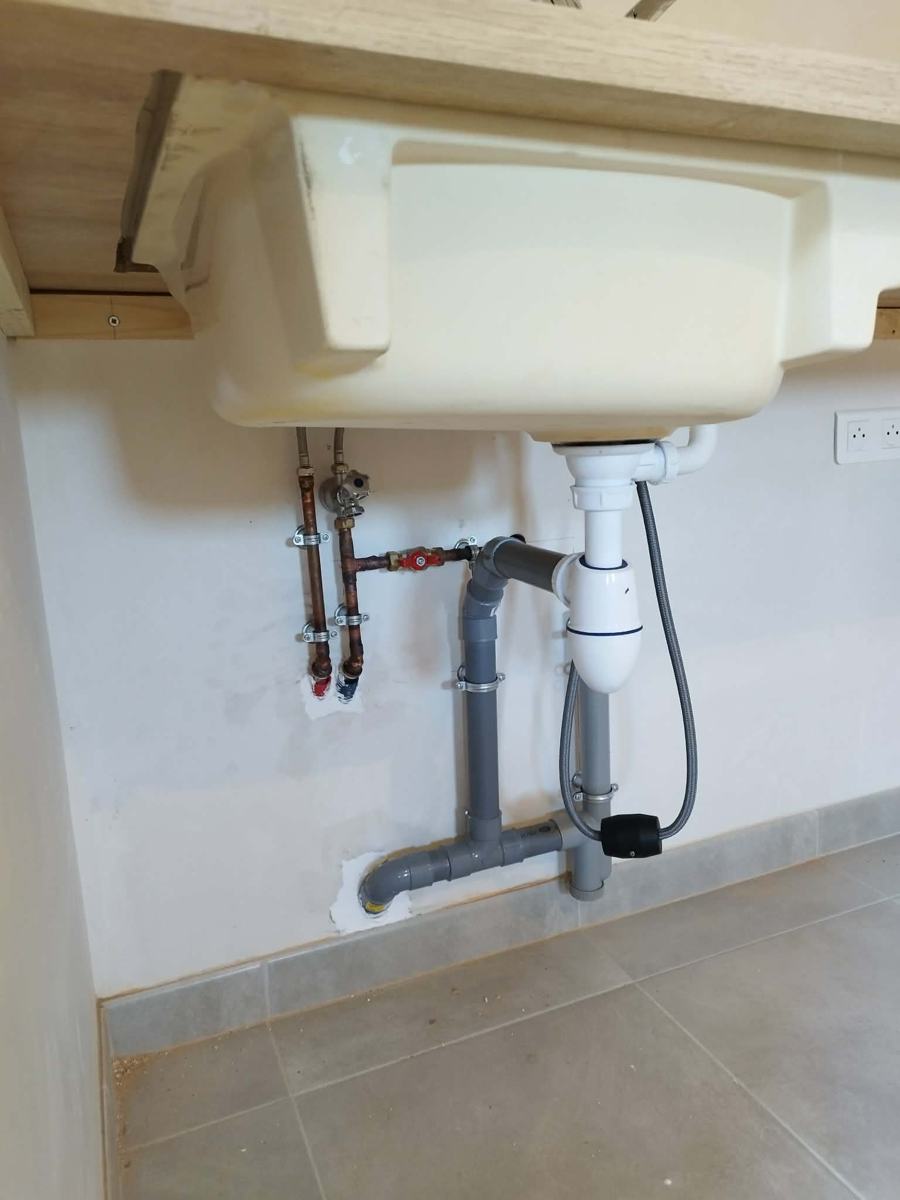 Alimentations cuivre et évacuation PVC sous un évier